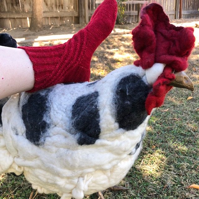 finished red wool sock posed with wool chicken footstool